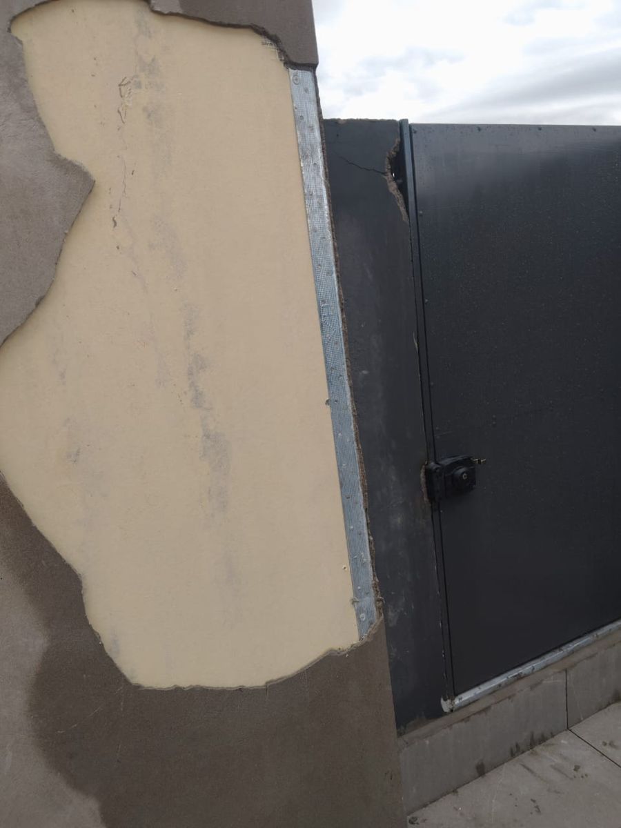 Estuco de fachada desprendido que deja a la vista la plancha de aislación y el esquinero metálico