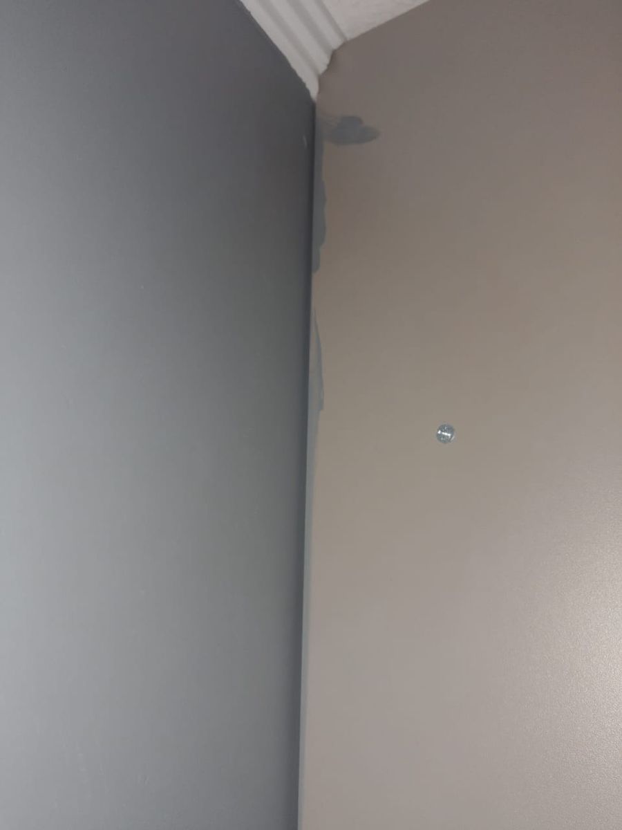 Costado de mueble de cocina junto a un muro gris, con pintura en la melamina y la junta vertical sin silicona